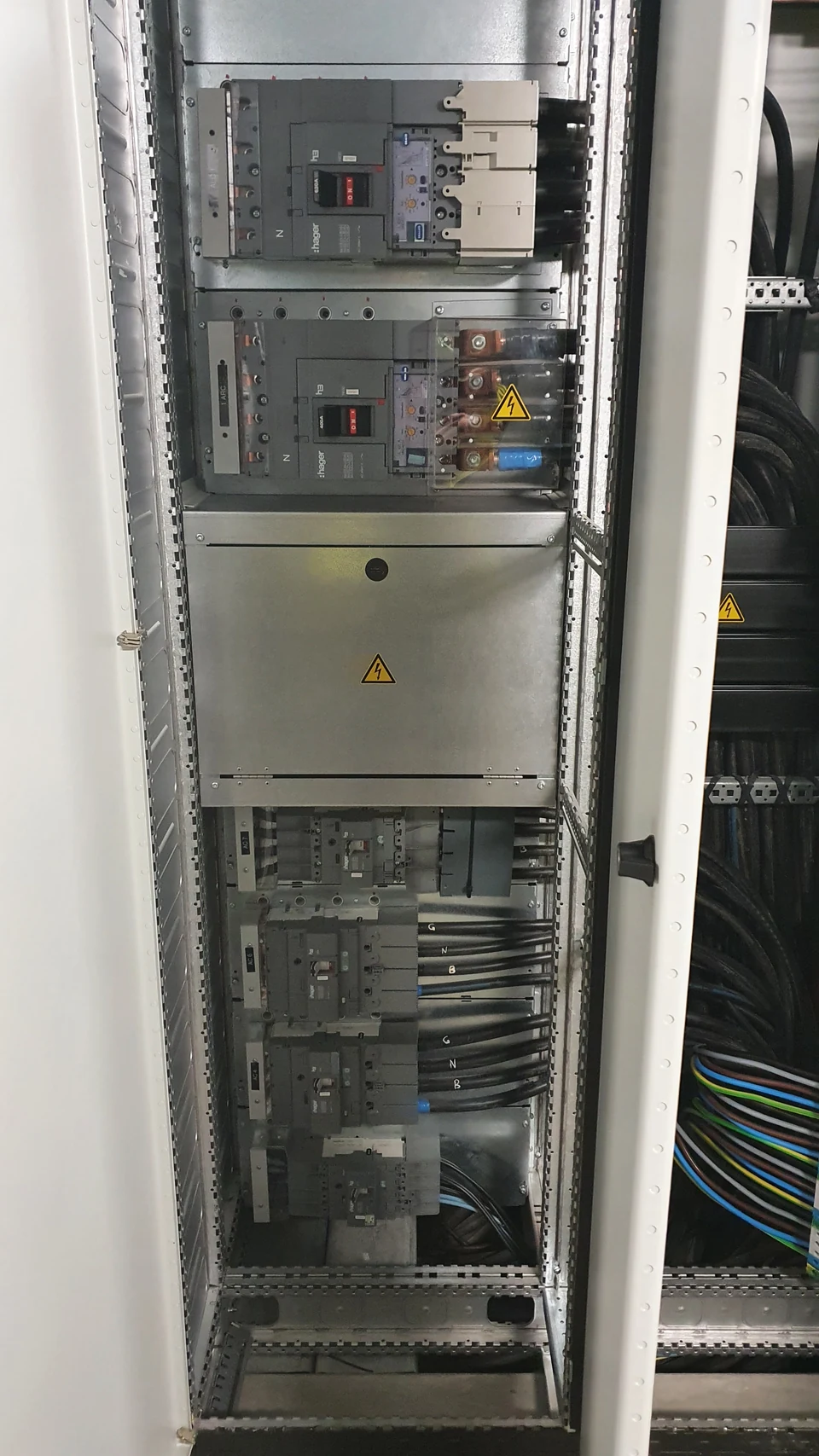 Intérieur d’un tableau électrique avec appareillage de puissance, protections et raccordements pour le comptage